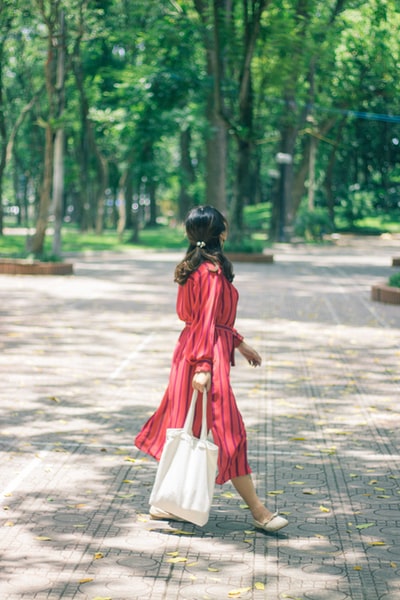 Dressed in red clothes during the day a woman walking on the sidewalk
